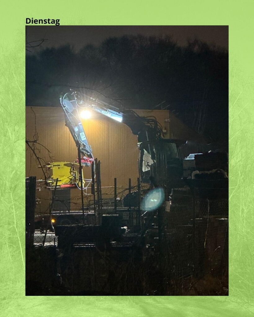 Bagger mit Aufsatz zum Bäumefällen vor der Halle von BM-Bau, das Foto ist von 6 Uhr morgens, es ist dunkel.