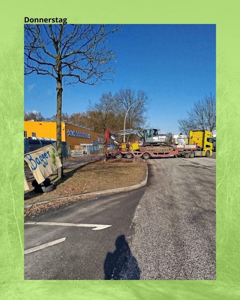Foto von der Straße vor BM-Bau. Ein Tieflader holt den Bagger und Zubehör ab. 